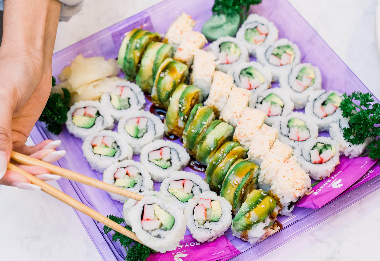 Chopsticks picking up a California Roll sushi